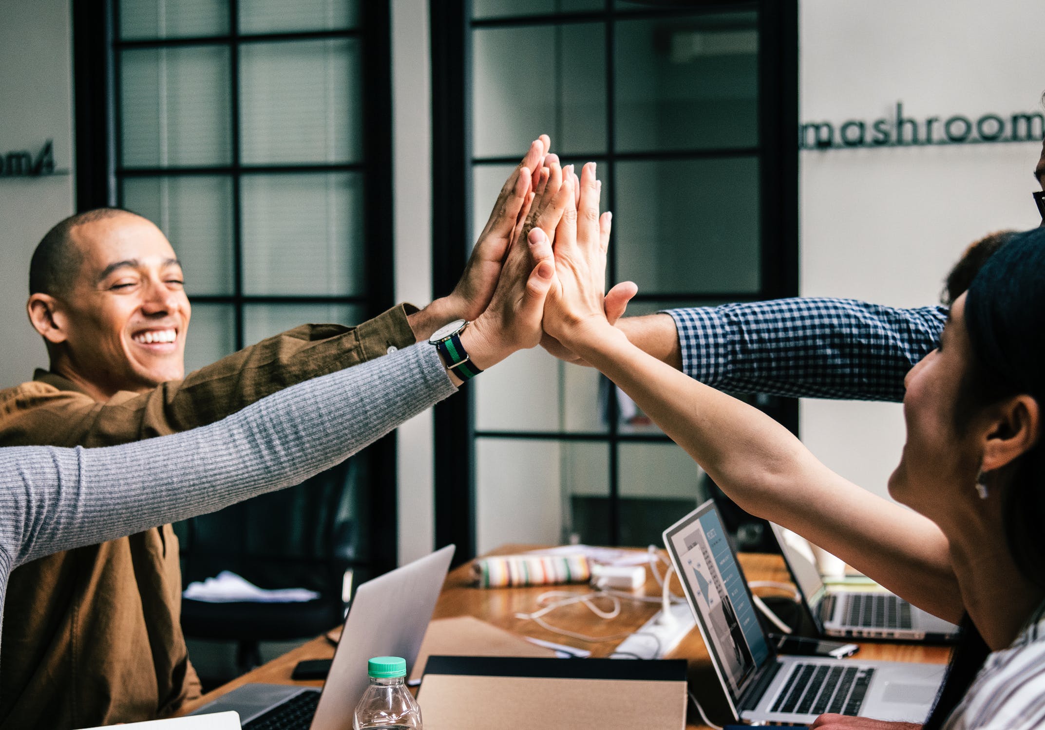 Work group of men and women high five over the discussion of B2B sales