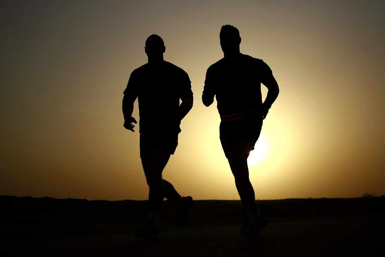 Two people perspirating while running at sunset